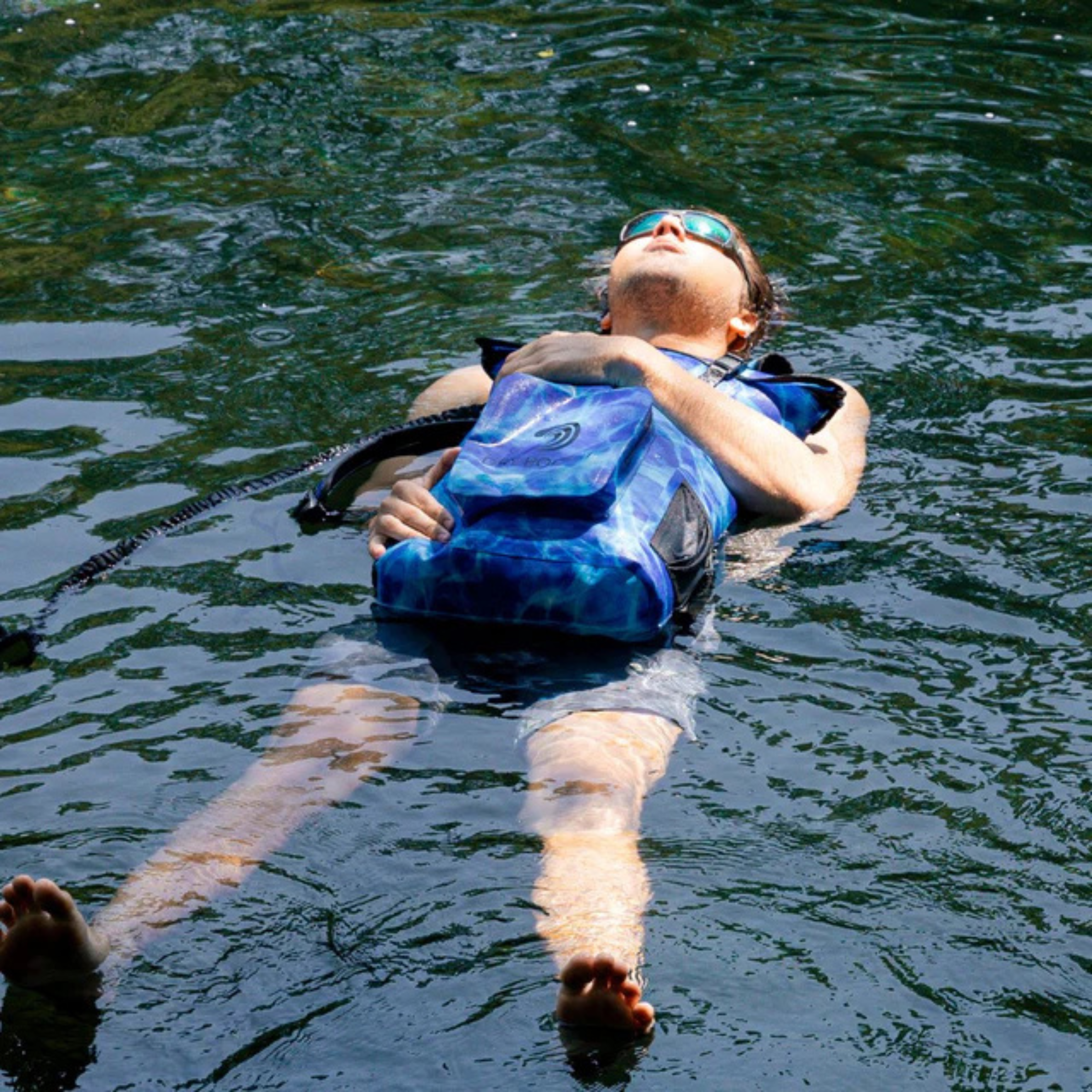 Man floating on a Dry Pocket waterproof floating backpack dry bag.