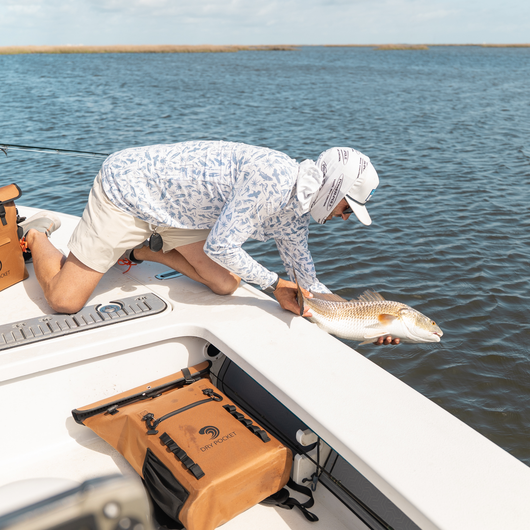 Man fishing with fish in hand and a dry pocket dry bag
